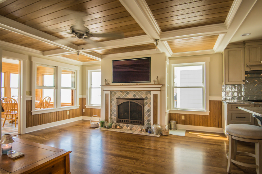 Imagen de sala de estar abierta marinera grande con paredes beige, suelo de madera en tonos medios, todas las chimeneas, pared multimedia y suelo marrón