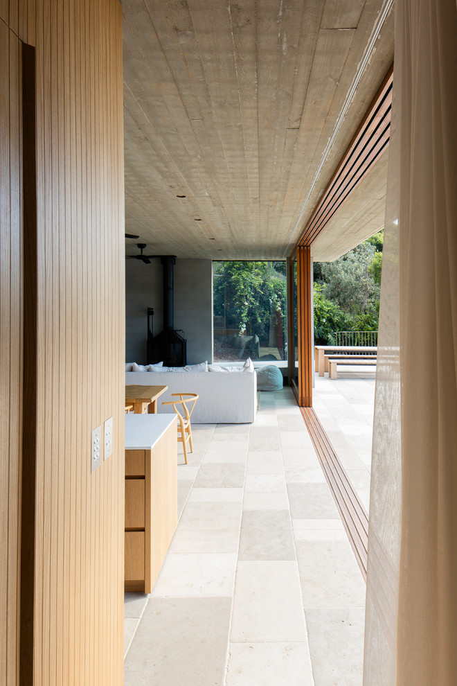 Imagen de sala de estar abierta costera de tamaño medio con paredes grises, suelo de piedra caliza, todas las chimeneas y suelo beige