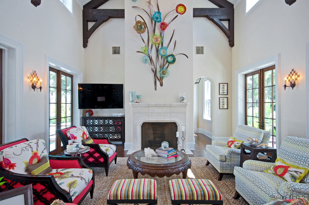Immagine di un soggiorno tropicale chiuso con pareti bianche, camino classico, cornice del camino in pietra e porta TV ad angolo