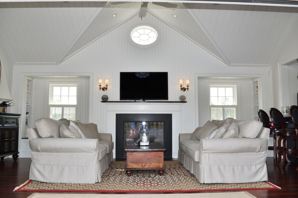 Mittelgroßes, Offenes Maritimes Wohnzimmer mit weißer Wandfarbe, braunem Holzboden, Kamin, Kaminumrandung aus Holz, TV-Wand und braunem Boden in Boston