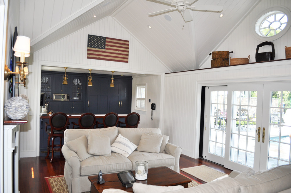 Mittelgroßes, Offenes Maritimes Wohnzimmer mit weißer Wandfarbe, braunem Holzboden, Kamin, Kaminumrandung aus Holz, TV-Wand und braunem Boden in Boston
