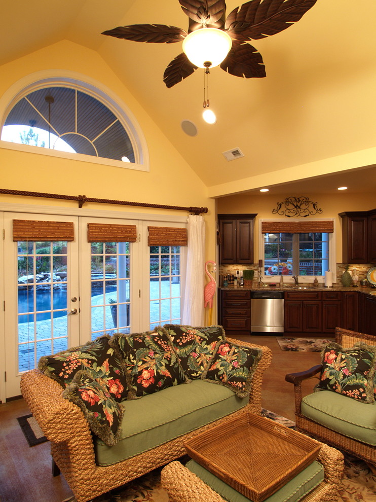 Imagen de sala de estar abierta tropical de tamaño medio con suelo de cemento y paredes amarillas