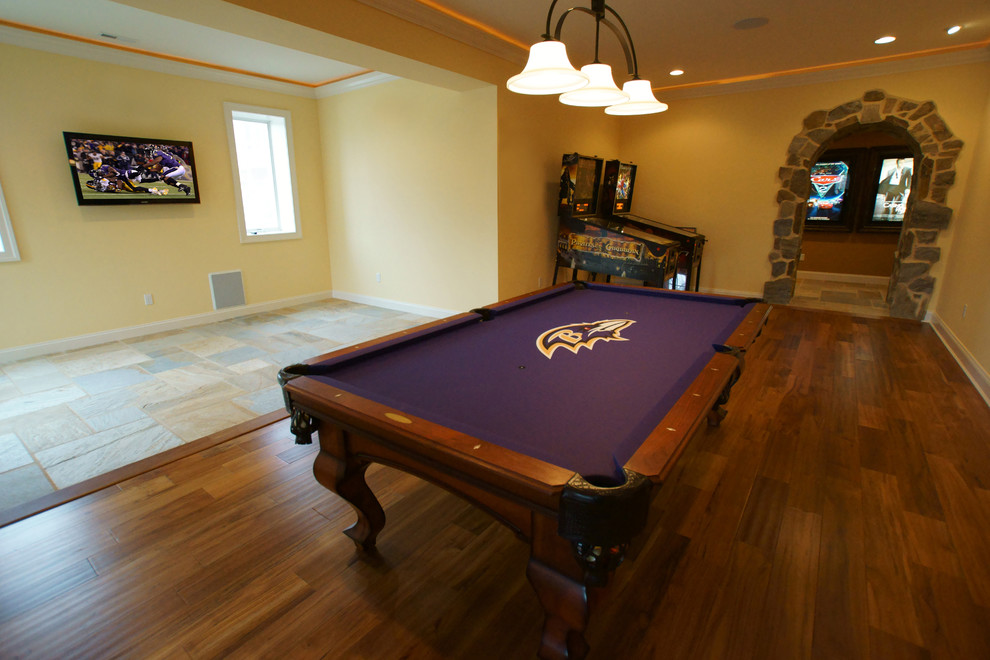 Imagen de sala de juegos en casa abierta clásica renovada de tamaño medio sin chimenea con paredes amarillas, suelo de madera en tonos medios y televisor colgado en la pared