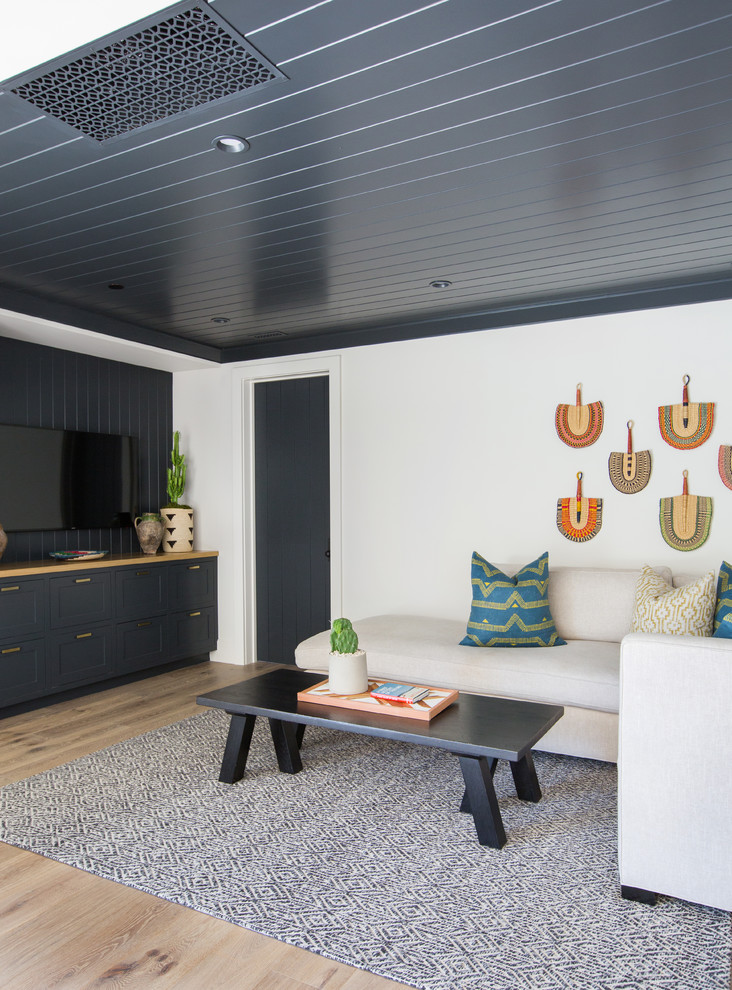 Стильный дизайн: гостиная комната в морском стиле с белыми стенами, светлым паркетным полом, телевизором на стене, бежевым полом и ковром на полу - последний тренд