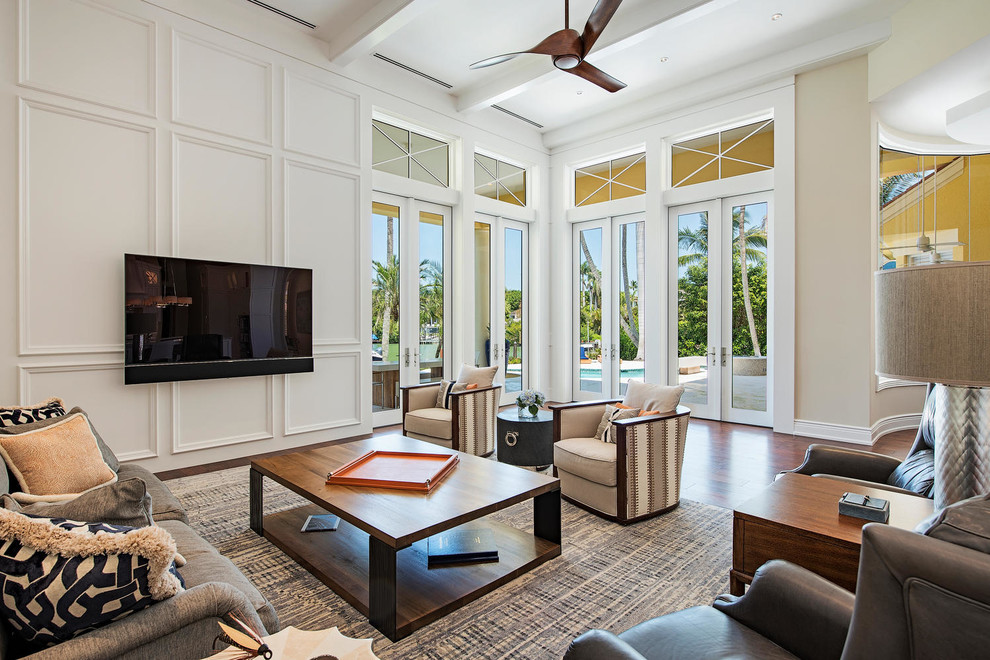 Mediterranes Wohnzimmer mit beiger Wandfarbe, braunem Holzboden und TV-Wand in Miami