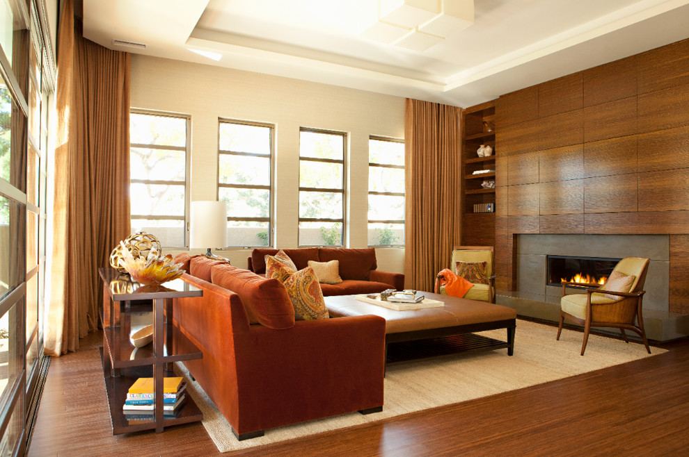 Modernes Wohnzimmer mit beiger Wandfarbe, braunem Holzboden, Gaskamin und Kaminumrandung aus Beton in Orange County