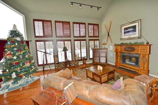 Cette photo montre une grande salle de séjour tendance ouverte avec un mur beige, un sol en bois brun, une cheminée double-face et un manteau de cheminée en bois.