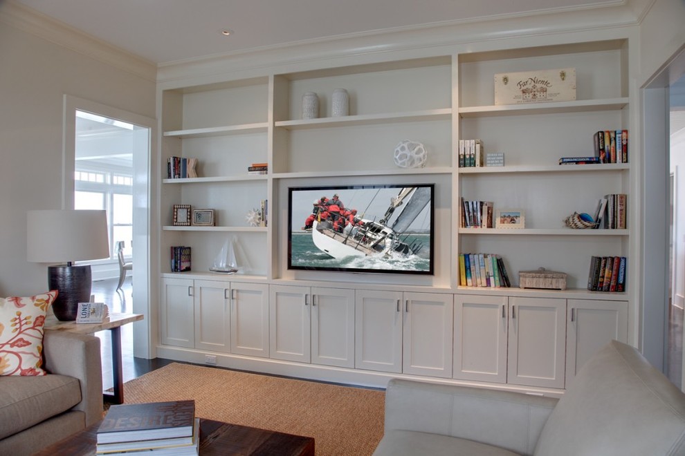 Imagen de sala de estar costera sin chimenea con paredes blancas, suelo de madera oscura y pared multimedia