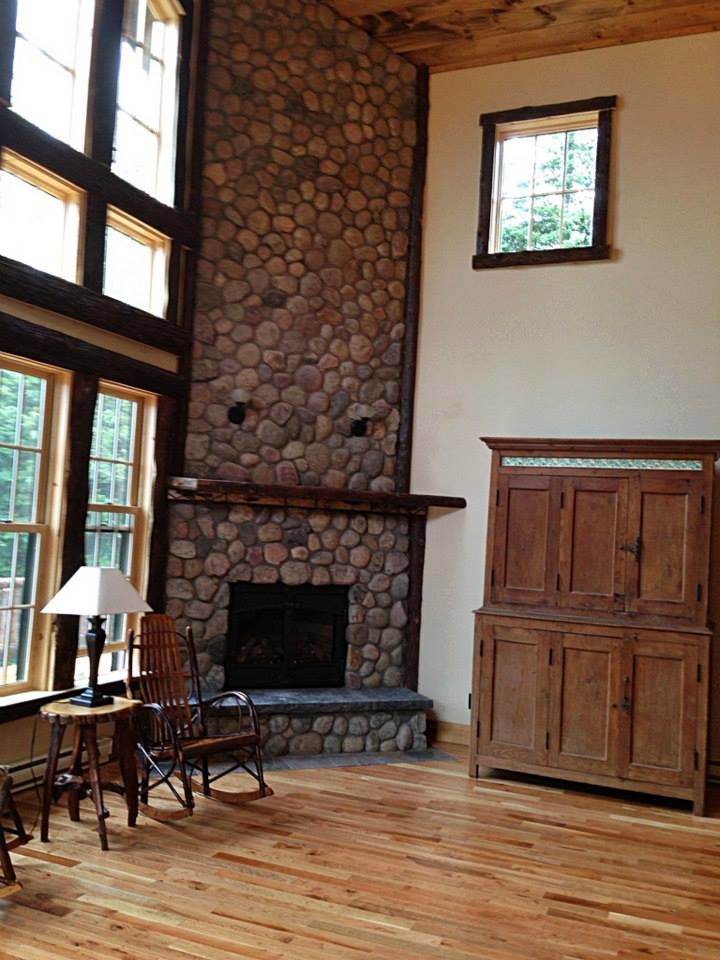 This is an example of a medium sized rustic mezzanine games room in Burlington with beige walls, light hardwood flooring and a corner fireplace.