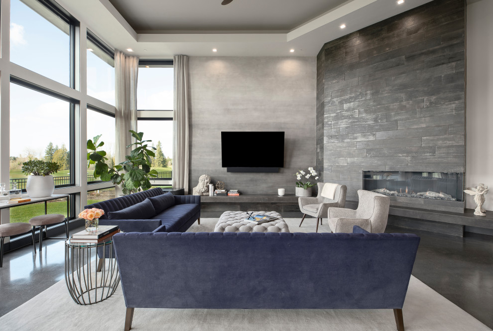 Imagen de sala de estar abierta contemporánea grande con paredes grises, suelo de cemento, chimenea de esquina, marco de chimenea de baldosas y/o azulejos, televisor colgado en la pared, suelo gris y bandeja