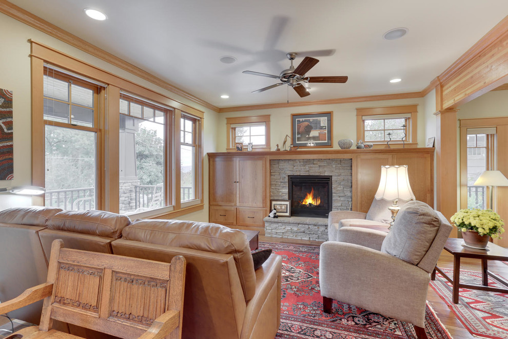 Inspiration pour une salle de séjour craftsman de taille moyenne avec un sol en bois brun et un manteau de cheminée en pierre.
