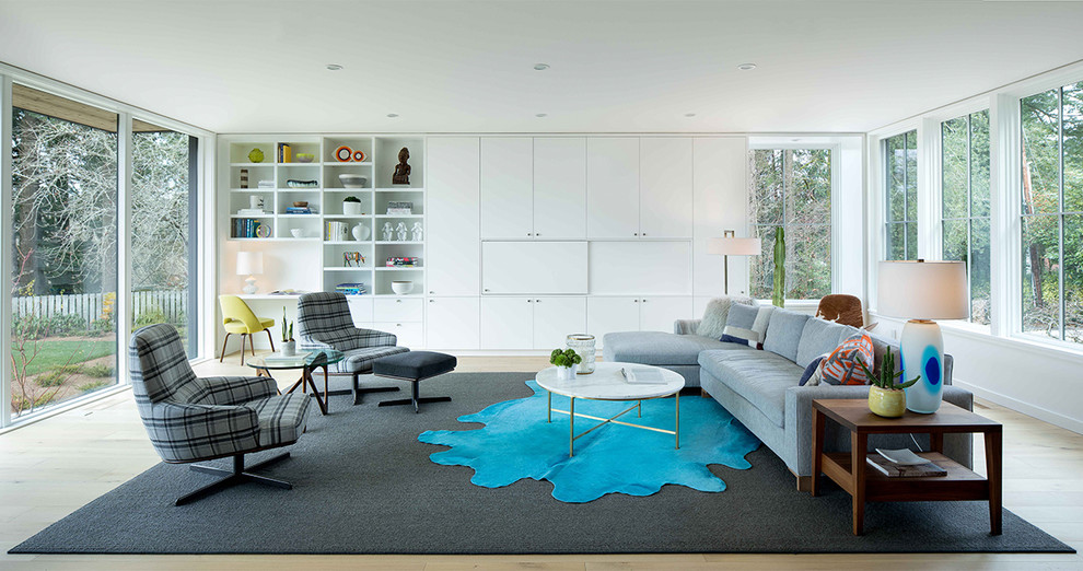 Modelo de sala de estar actual con suelo de madera en tonos medios, televisor retractable y suelo marrón