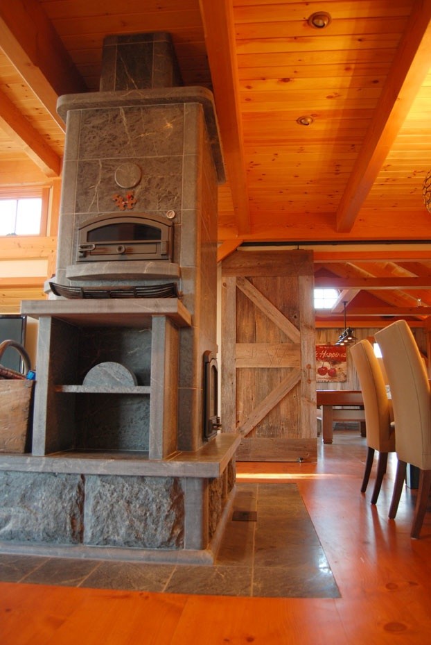 Ejemplo de sala de estar abierta tradicional de tamaño medio con paredes blancas, suelo de madera en tonos medios, estufa de leña y marco de chimenea de piedra