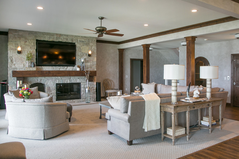 Example of a huge transitional open concept medium tone wood floor and brown floor family room design in Milwaukee with gray walls, a standard fireplace, a stone fireplace and a wall-mounted tv