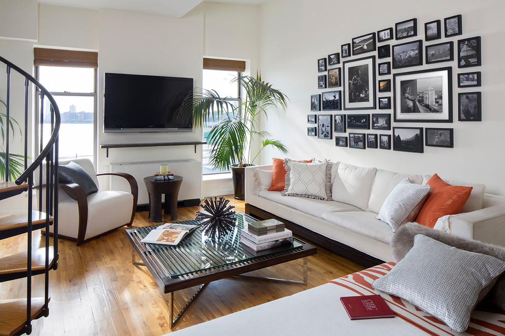 Family room - contemporary open concept medium tone wood floor family room idea in New York with white walls and a wall-mounted tv