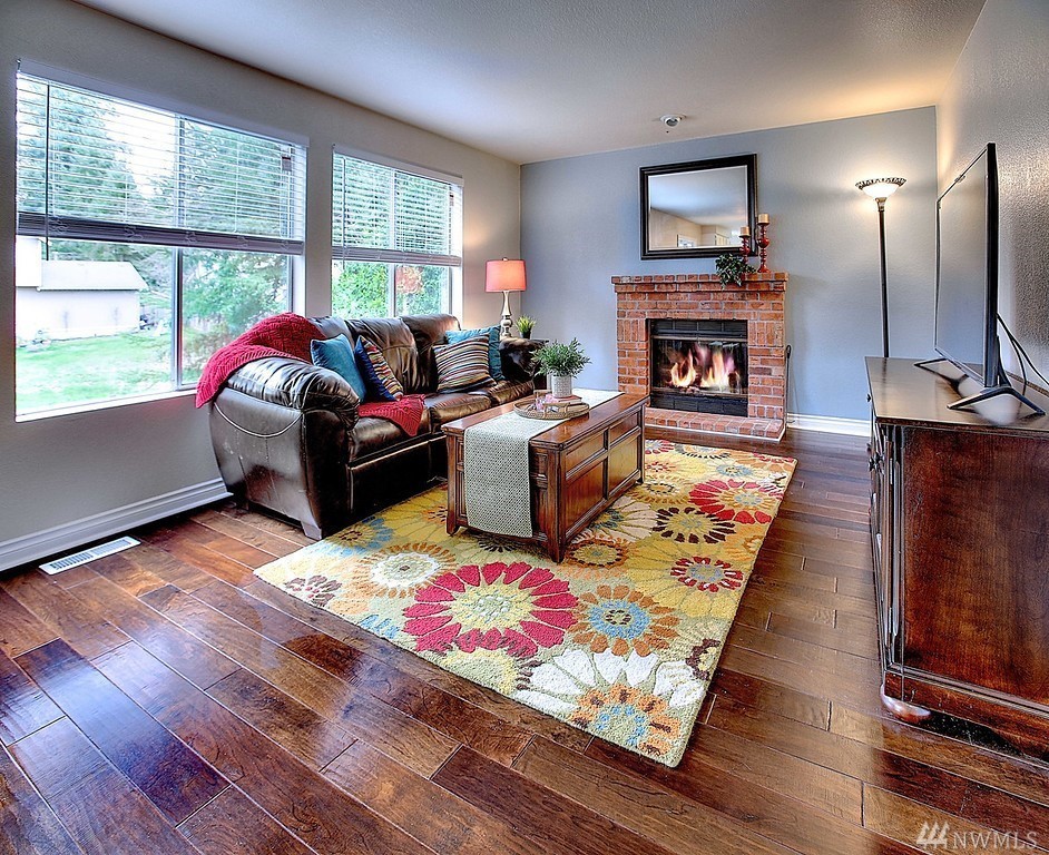 Idée de décoration pour une salle de séjour tradition ouverte avec un mur bleu, un sol en bois brun, un manteau de cheminée en brique, un téléviseur indépendant et un sol marron.