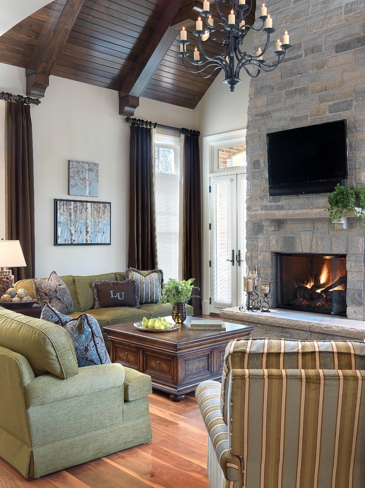 Klassisches Wohnzimmer mit beiger Wandfarbe, braunem Holzboden, Kamin, Kaminumrandung aus Stein und TV-Wand in St. Louis