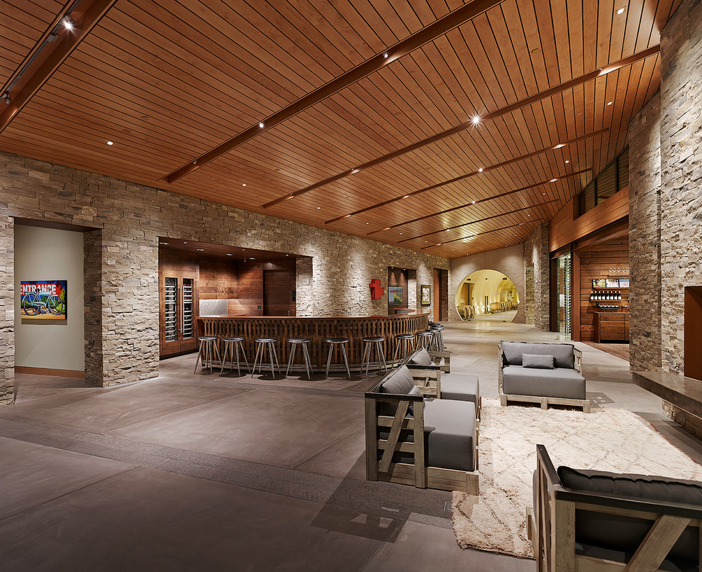 На фото: гостиная комната в современном стиле с домашним баром, бетонным полом и стандартным камином