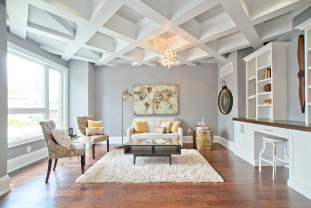 Modelo de sala de estar con biblioteca abierta clásica renovada sin chimenea con paredes grises, suelo de madera clara, televisor retractable y suelo marrón