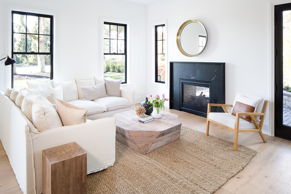 Offenes Klassisches Wohnzimmer mit weißer Wandfarbe, hellem Holzboden, Tunnelkamin, Kaminumrandung aus Stein und schwarzem Boden in Seattle