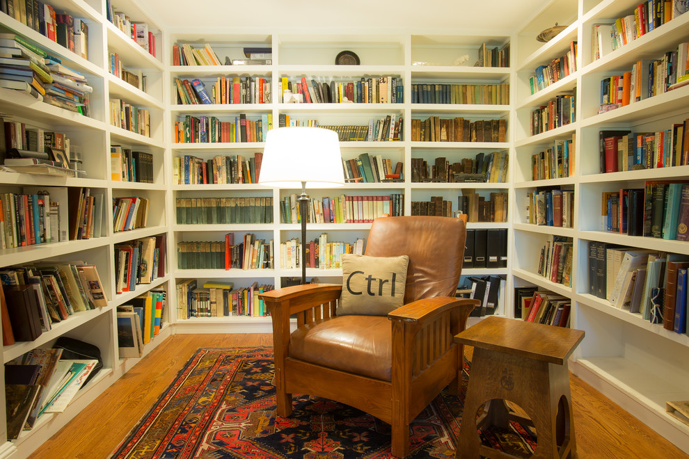 Fernseherlose Klassische Bibliothek mit weißer Wandfarbe und braunem Holzboden in New York