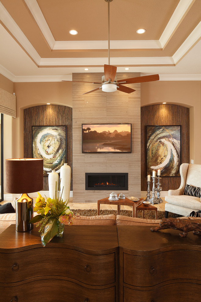Modelo de sala de estar abierta clásica con paredes beige, suelo de baldosas de porcelana, chimenea lineal, televisor colgado en la pared y suelo beige