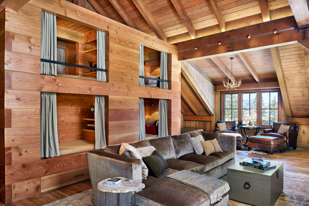 Réalisation d'une salle de séjour chalet de taille moyenne avec un sol en bois brun, un mur marron, une cheminée standard, un manteau de cheminée en pierre et un téléviseur encastré.