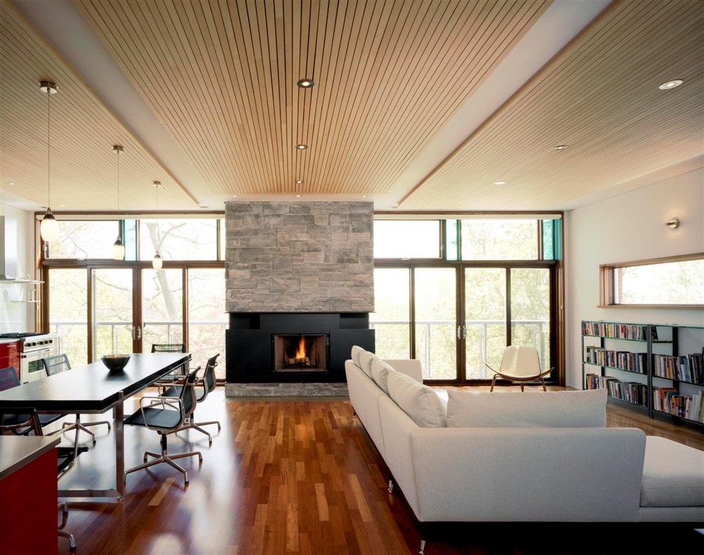 Réalisation d'une salle de séjour design ouverte avec un mur blanc, un sol en bois brun, un manteau de cheminée en pierre et une cheminée standard.