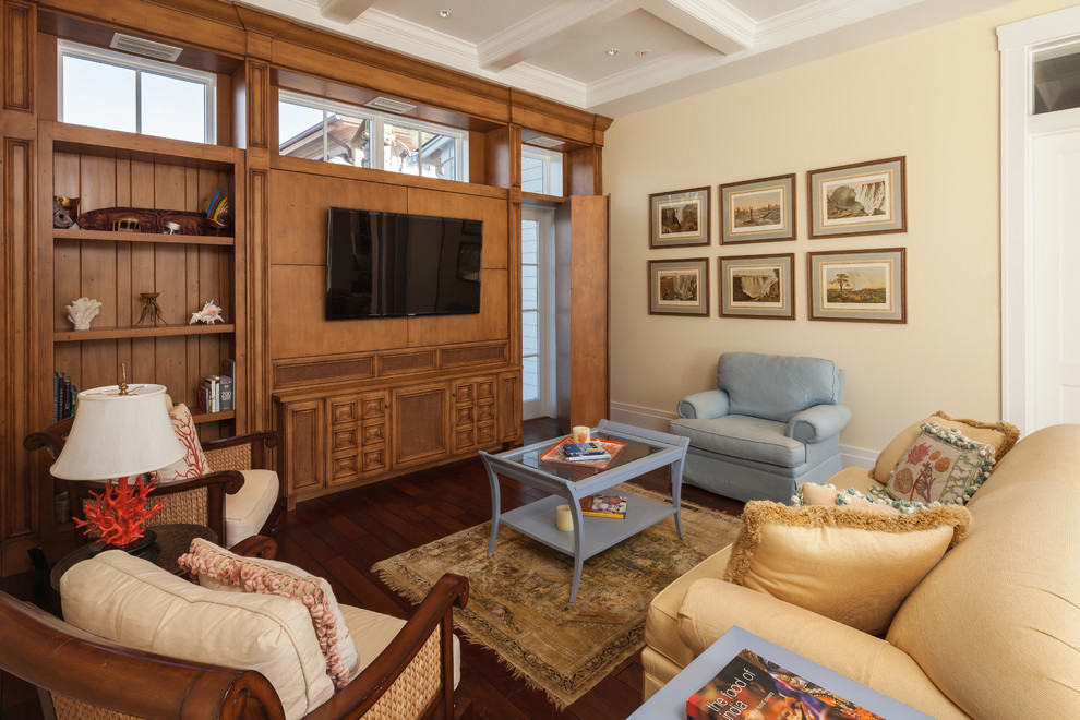 Ejemplo de sala de estar cerrada tropical con paredes beige, suelo de madera oscura y televisor colgado en la pared