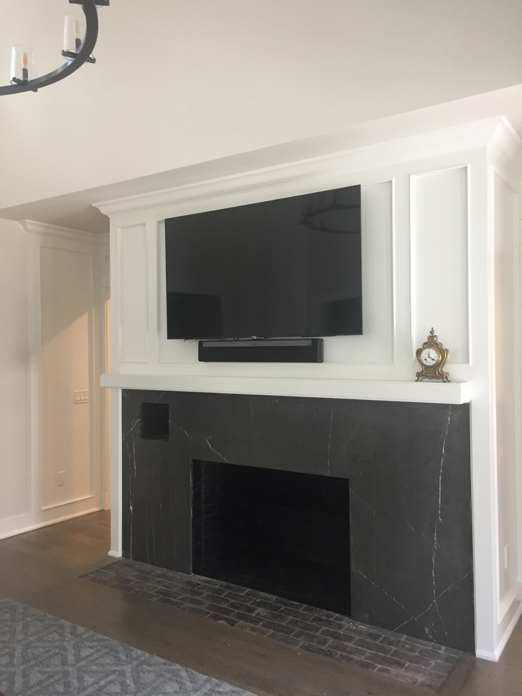 Пример оригинального дизайна: открытая гостиная комната среднего размера в стиле неоклассика (современная классика) с серыми стенами, паркетным полом среднего тона, стандартным камином, фасадом камина из камня, телевизором на стене и серым полом