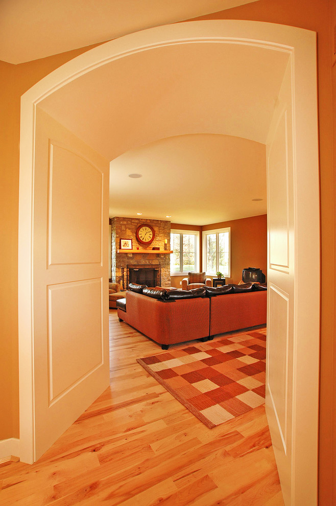Пример оригинального дизайна: открытая гостиная комната в классическом стиле с коричневыми стенами, светлым паркетным полом, стандартным камином и фасадом камина из камня