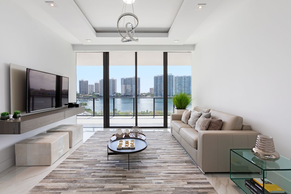 Example of a trendy open concept marble floor living room design in Miami with white walls, no fireplace and a wall-mounted tv