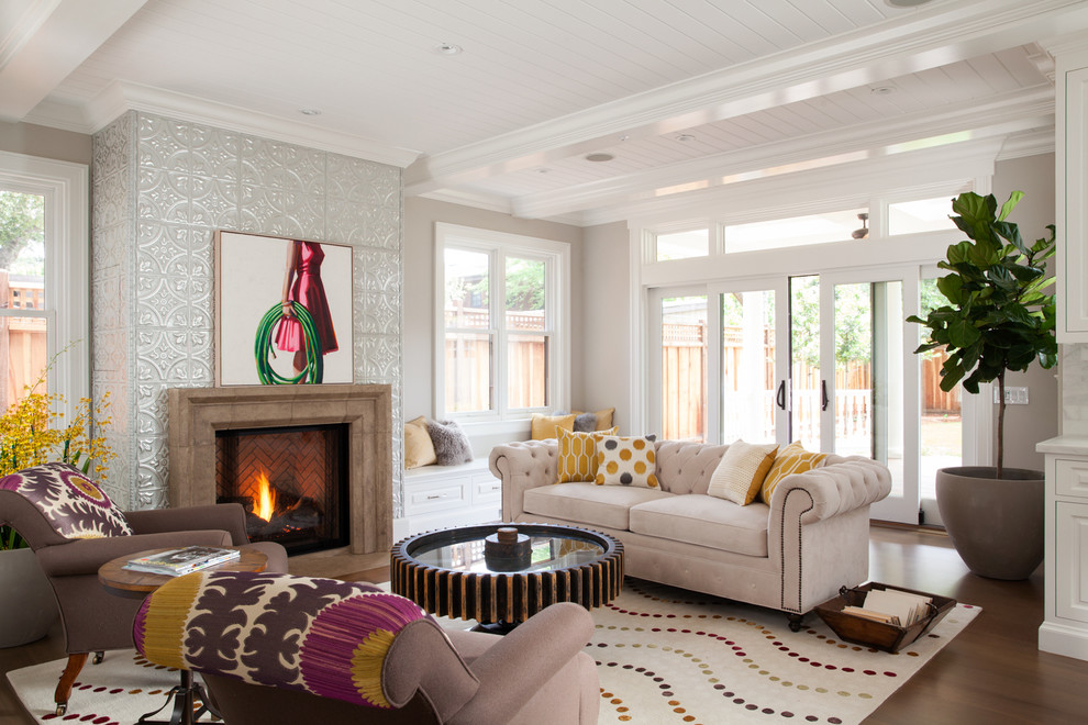 Diseño de sala de estar clásica con paredes grises, suelo de madera en tonos medios, todas las chimeneas y marco de chimenea de metal