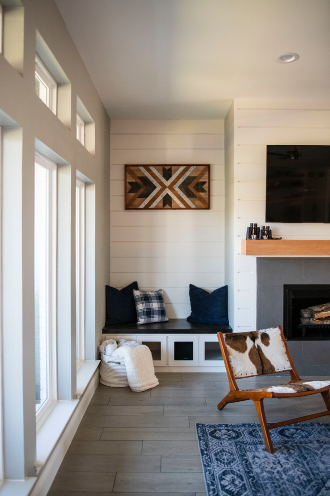 Cette photo montre une salle de séjour nature de taille moyenne et ouverte avec un mur blanc, un sol en carrelage de porcelaine, une cheminée standard, un manteau de cheminée en bois, un téléviseur fixé au mur et un sol gris.