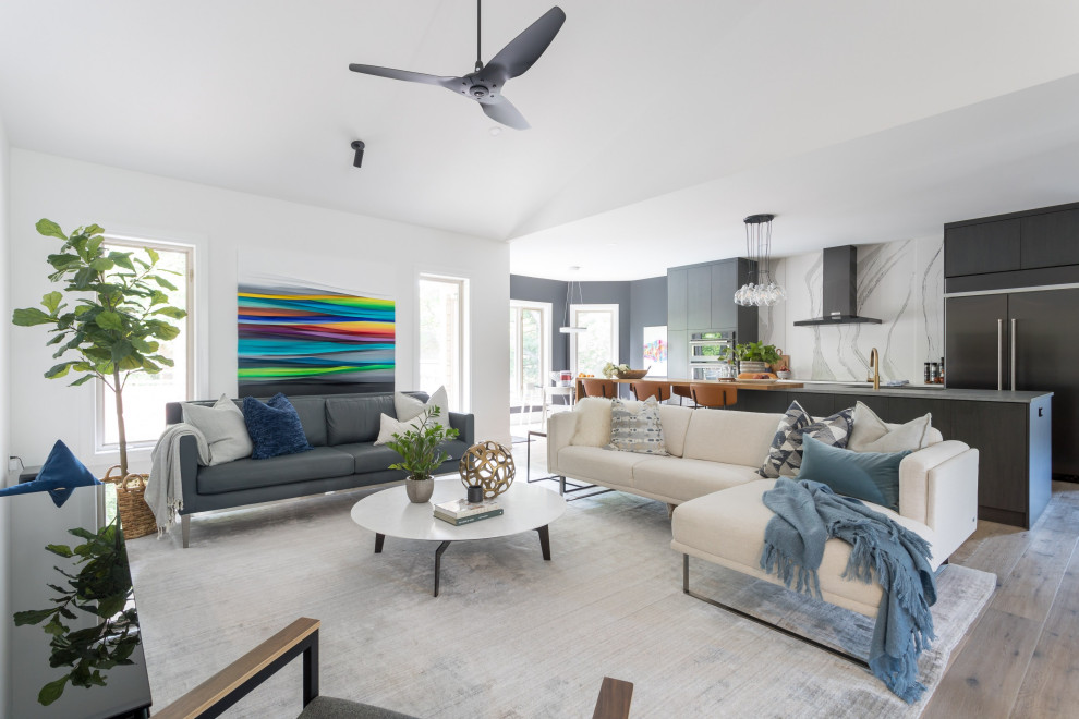 Modelo de sala de estar abierta minimalista grande sin chimenea con paredes blancas, suelo de madera en tonos medios, televisor colgado en la pared y suelo gris