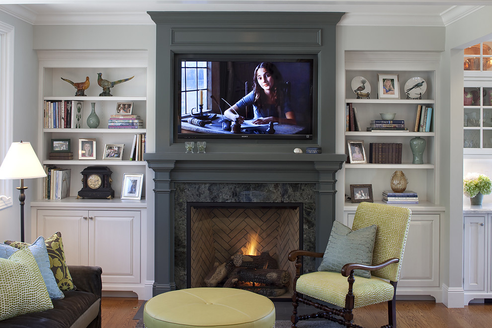 Inspiration for a timeless medium tone wood floor family room remodel in San Francisco with gray walls, a standard fireplace, a wall-mounted tv and a wood fireplace surround