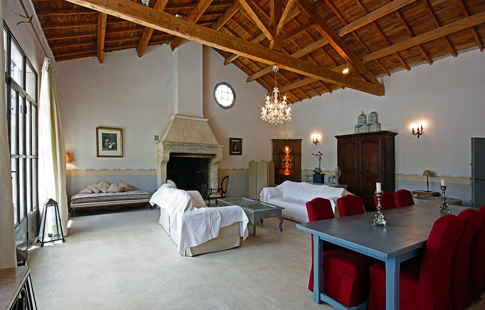 На фото: гостиная комната в стиле кантри с бежевыми стенами, полом из известняка, стандартным камином, фасадом камина из камня и скрытым телевизором с