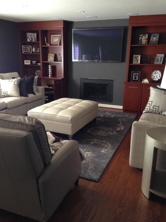 На фото: изолированная гостиная комната среднего размера в классическом стиле с серыми стенами, паркетным полом среднего тона, стандартным камином, фасадом камина из штукатурки, телевизором на стене и коричневым полом с