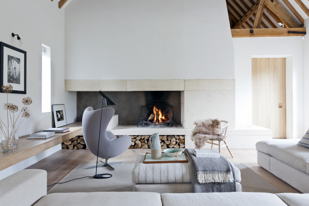 Photo of a large contemporary enclosed games room in Barcelona with white walls, light hardwood flooring, a standard fireplace, a stone fireplace surround and no tv.