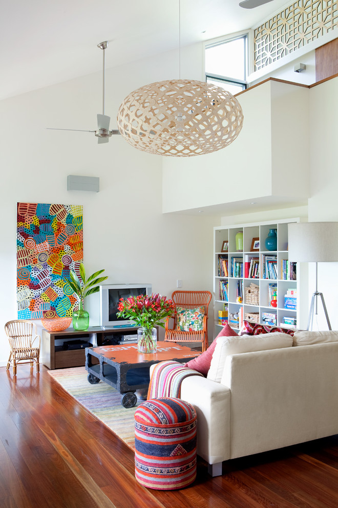 Example of a mid-sized trendy open concept medium tone wood floor and brown floor family room design in Brisbane with white walls and a tv stand