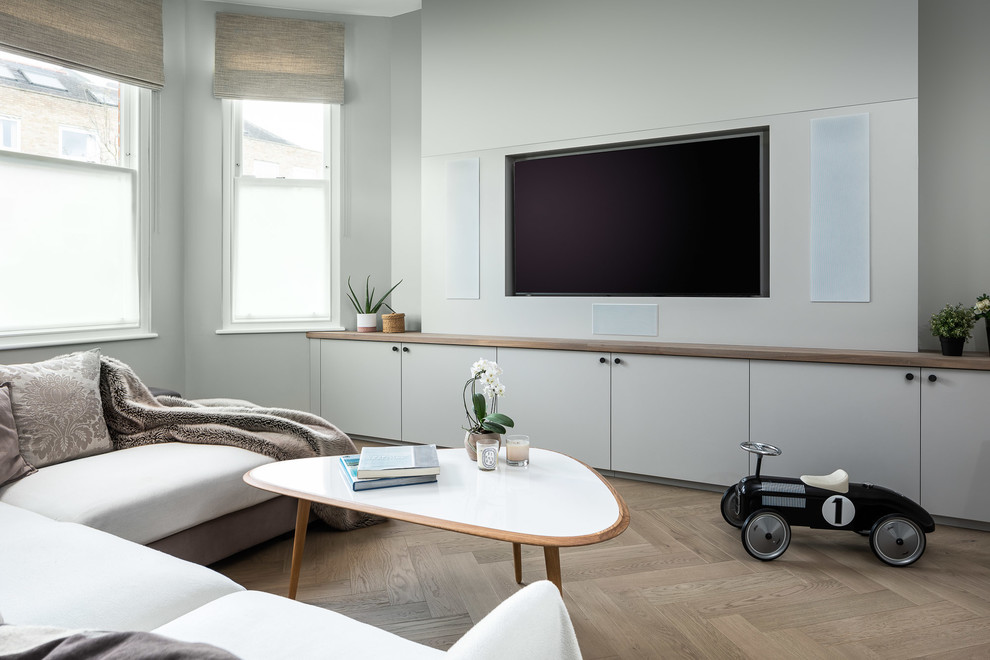 Стильный дизайн: гостиная комната в современном стиле с серыми стенами, светлым паркетным полом, мультимедийным центром и бежевым полом без камина - последний тренд