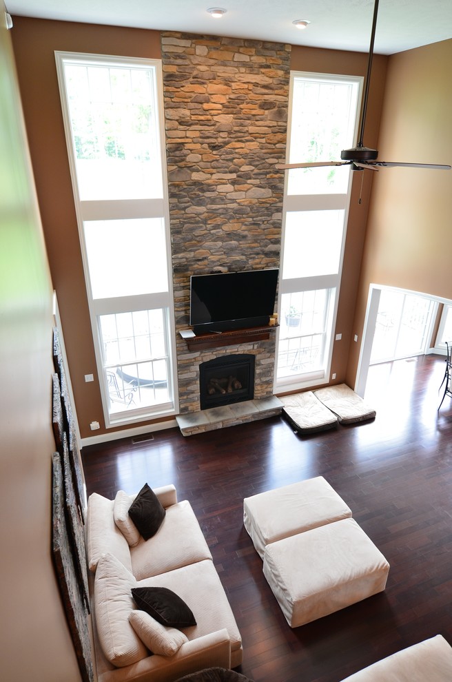 На фото: открытая гостиная комната среднего размера в стиле неоклассика (современная классика) с коричневыми стенами, паркетным полом среднего тона, стандартным камином и фасадом камина из камня