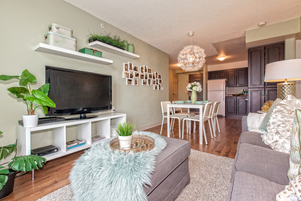 Réalisation d'une petite salle de séjour tradition ouverte avec un mur vert, un sol en bois brun et un téléviseur encastré.