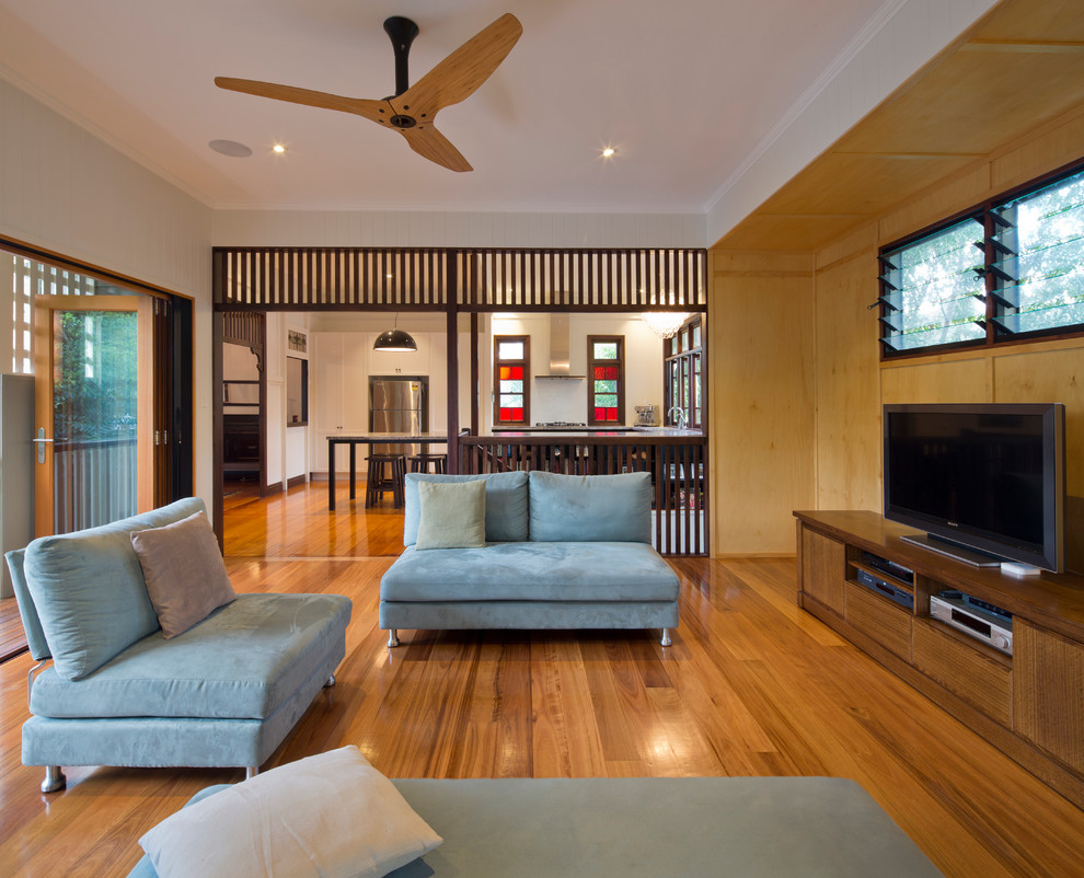 Modelo de sala de estar abierta actual sin chimenea con suelo de madera en tonos medios y televisor independiente