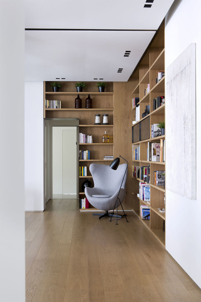 Ejemplo de sala de estar con biblioteca moderna con paredes blancas y suelo de madera clara