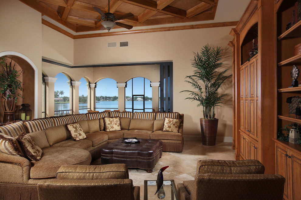 Modelo de sala de estar abierta tradicional sin chimenea con paredes beige, suelo de mármol y pared multimedia