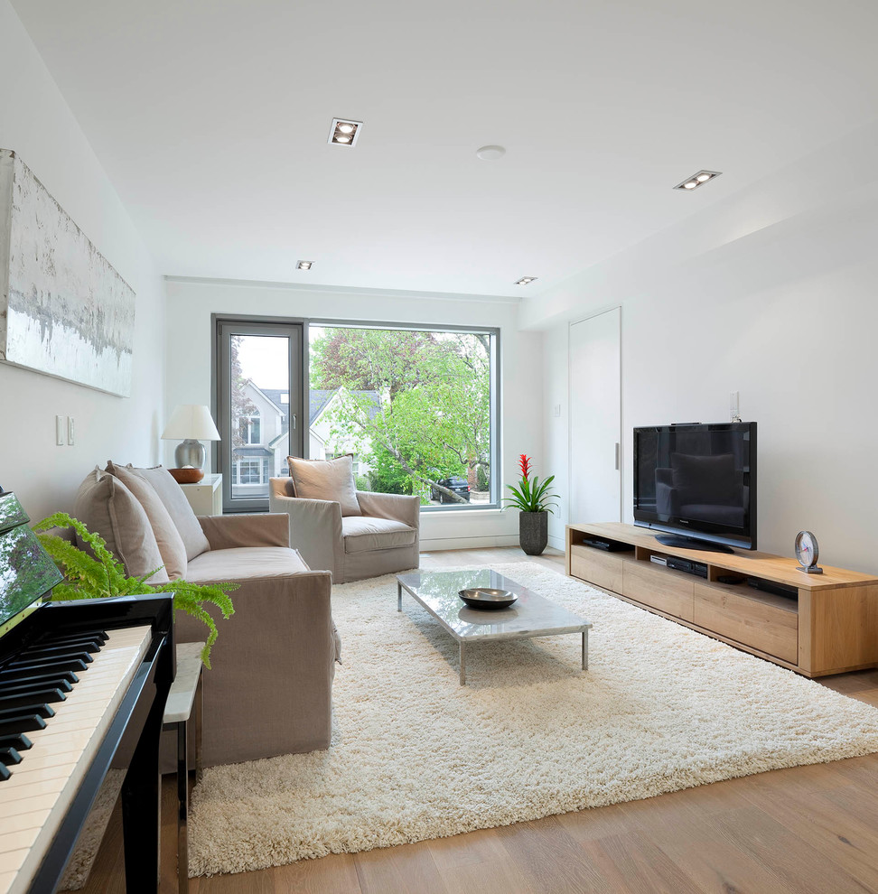 Ejemplo de sala de estar contemporánea sin chimenea con paredes blancas, suelo de madera clara y televisor independiente