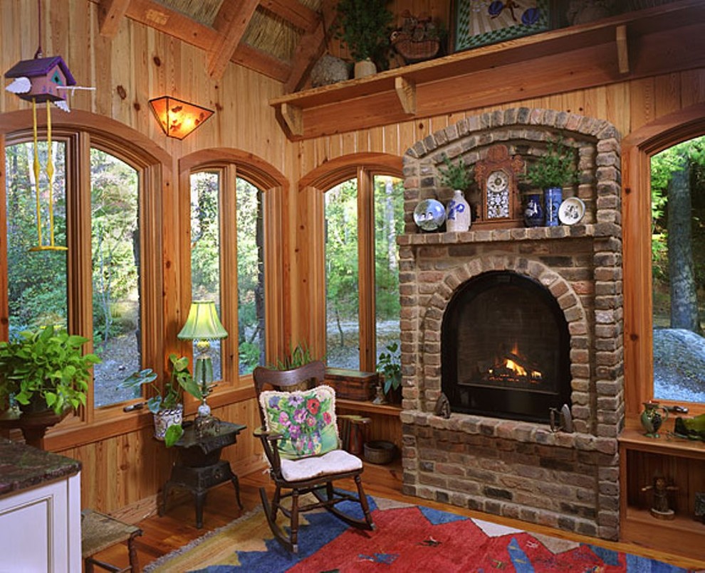 Foto de sala de estar tipo loft rural de tamaño medio sin televisor con paredes marrones, suelo de madera en tonos medios, todas las chimeneas y marco de chimenea de ladrillo