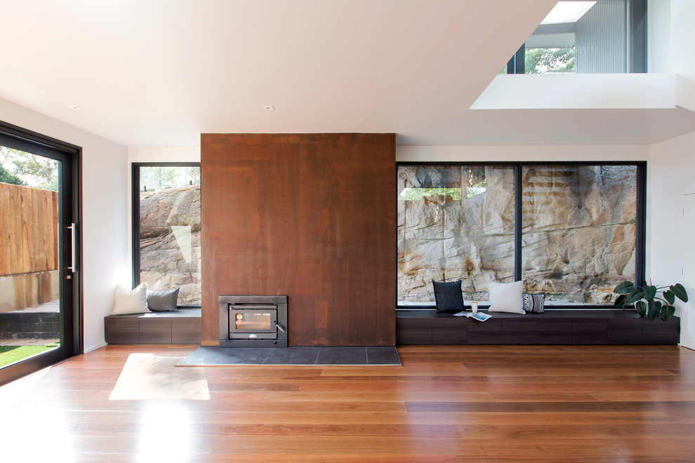 Ejemplo de sala de estar abierta actual grande sin chimenea y televisor con paredes blancas, suelo de madera en tonos medios y suelo marrón