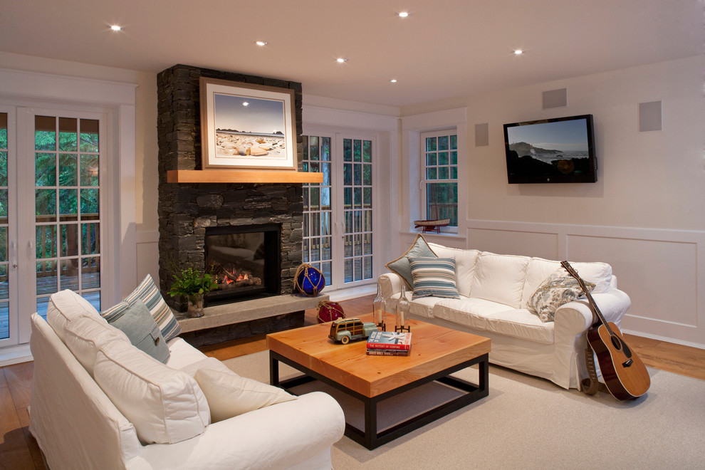 Klassisches Wohnzimmer mit beiger Wandfarbe, braunem Holzboden, Kamin, Kaminumrandung aus Stein und TV-Wand in Vancouver